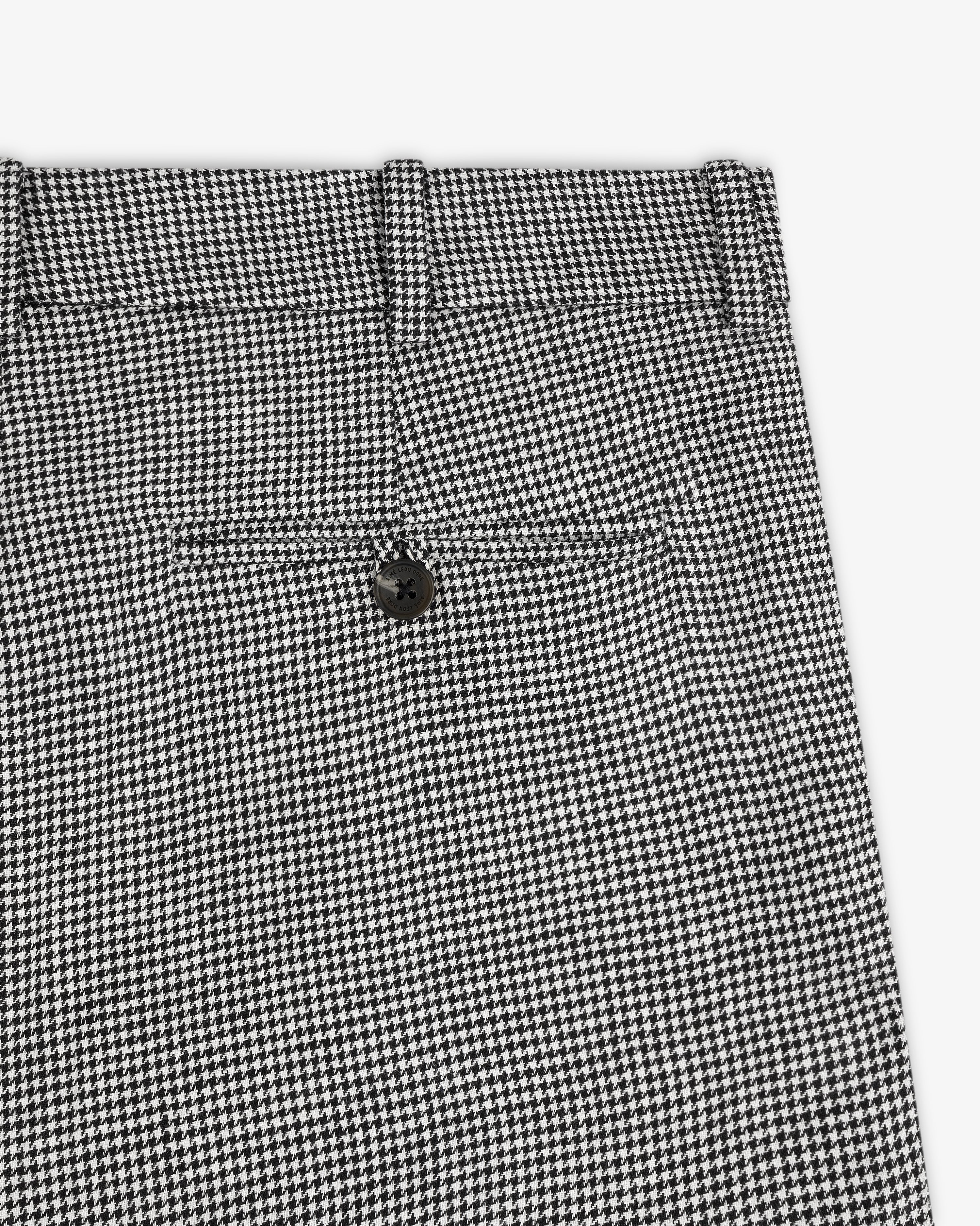 Close-up of Houndstooth Pleated Trouser in black and white, featuring a back pocket and black button.