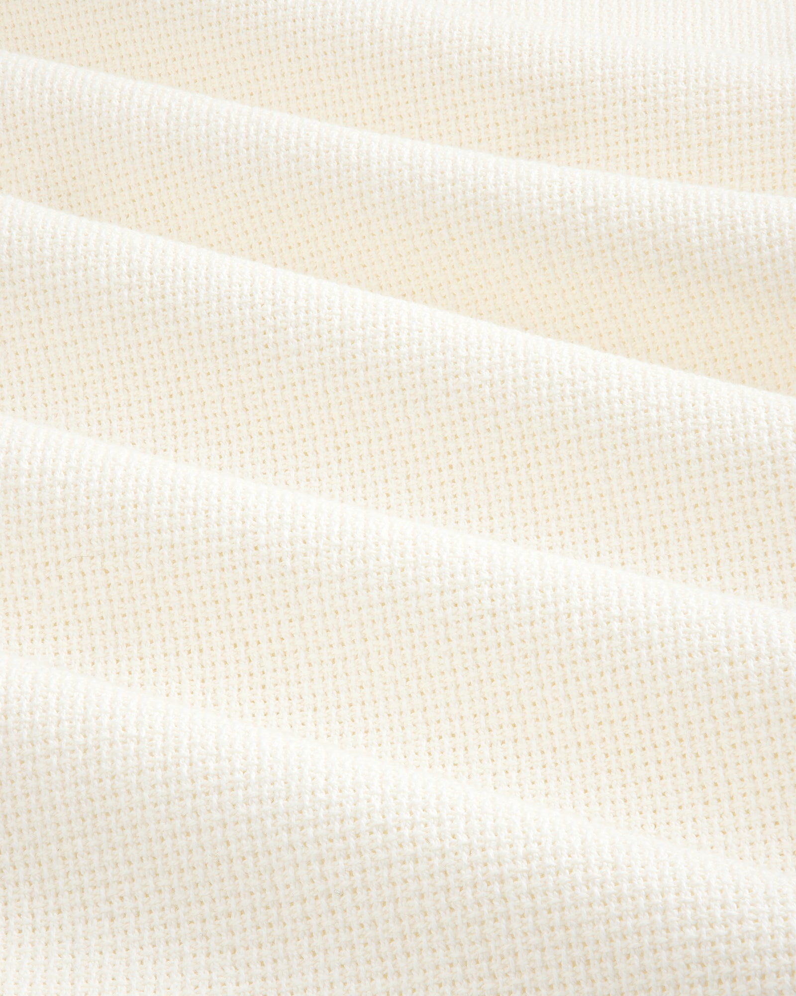 Close-up of cream-colored, textured fabric from the Wide Leg Shore Pant, featuring a subtle grid pattern and soft folds.
