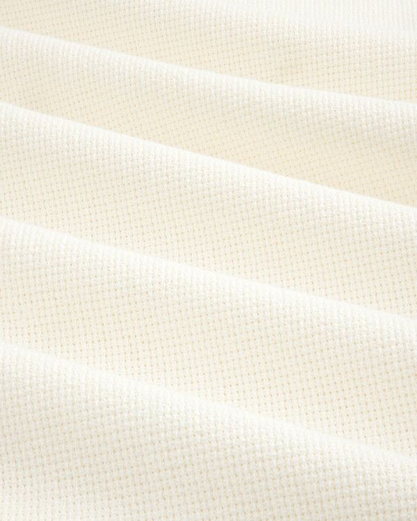 Close-up of cream-colored, textured fabric from the Wide Leg Shore Pant, featuring a subtle grid pattern and soft folds.