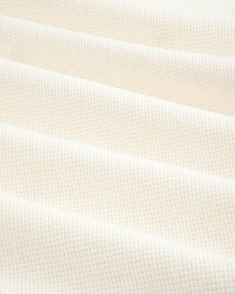 Close-up of cream-colored, textured fabric from the Wide Leg Shore Pant, featuring a subtle grid pattern and soft folds.