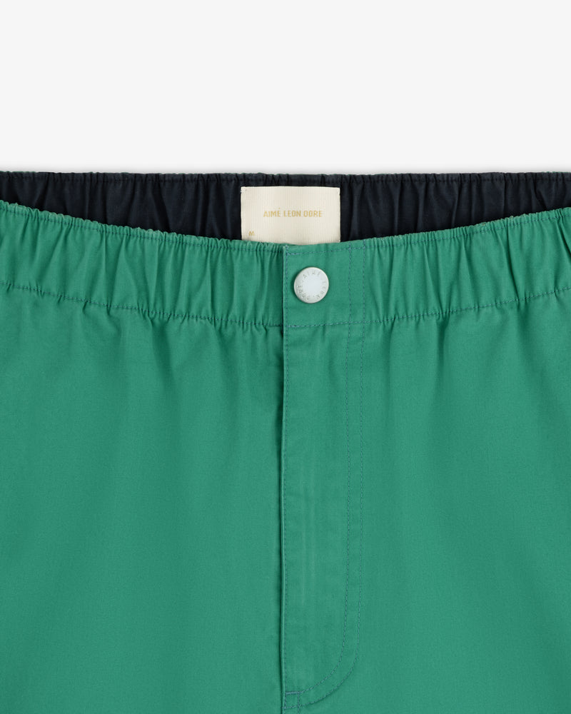 Close-up of Washed Cotton Windbreaker Pant in green, featuring an elastic waistband, front button, and white inner label.