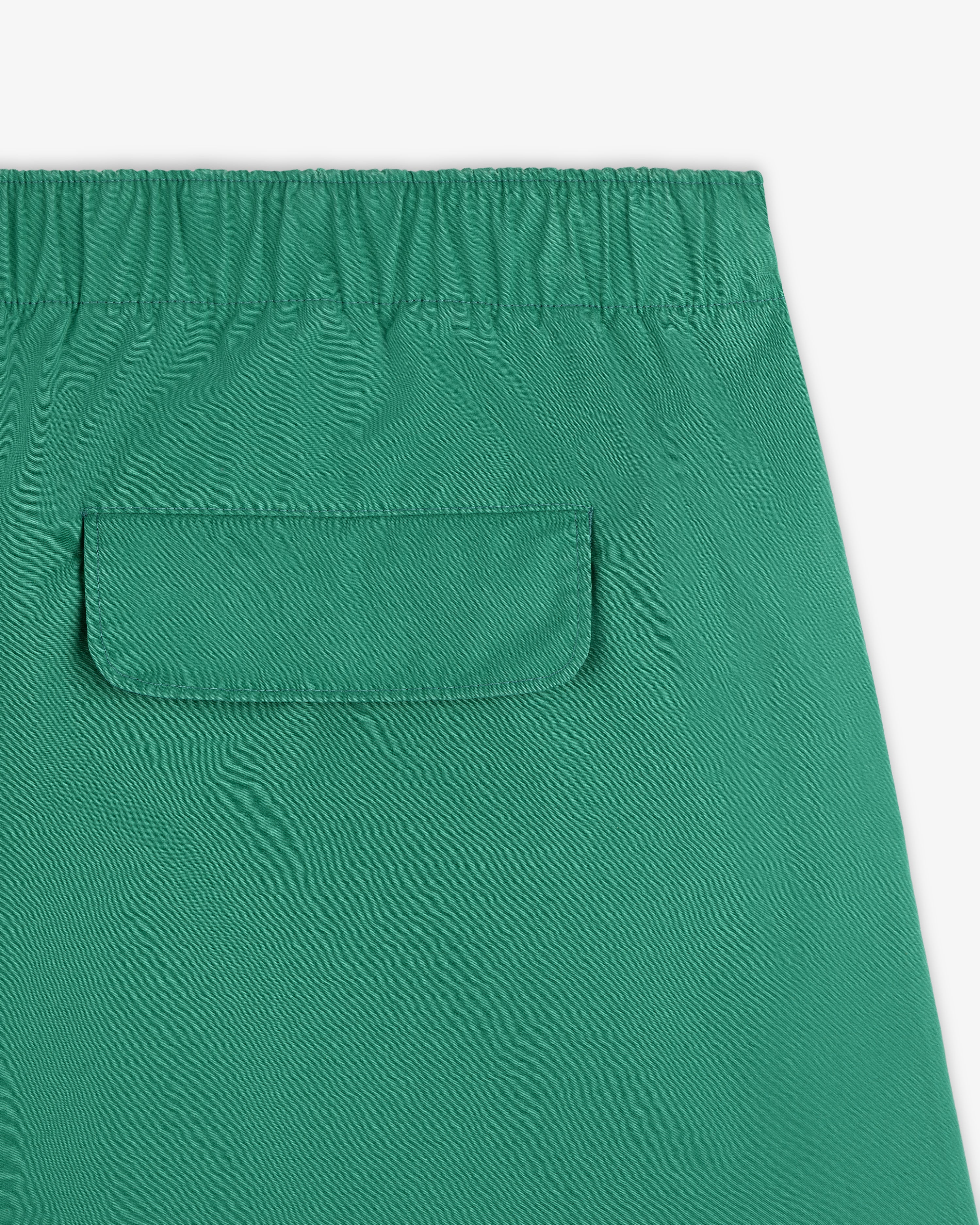 Close-up of Washed Cotton Windbreaker Pant in green, featuring an elastic waistband and a flap back pocket.