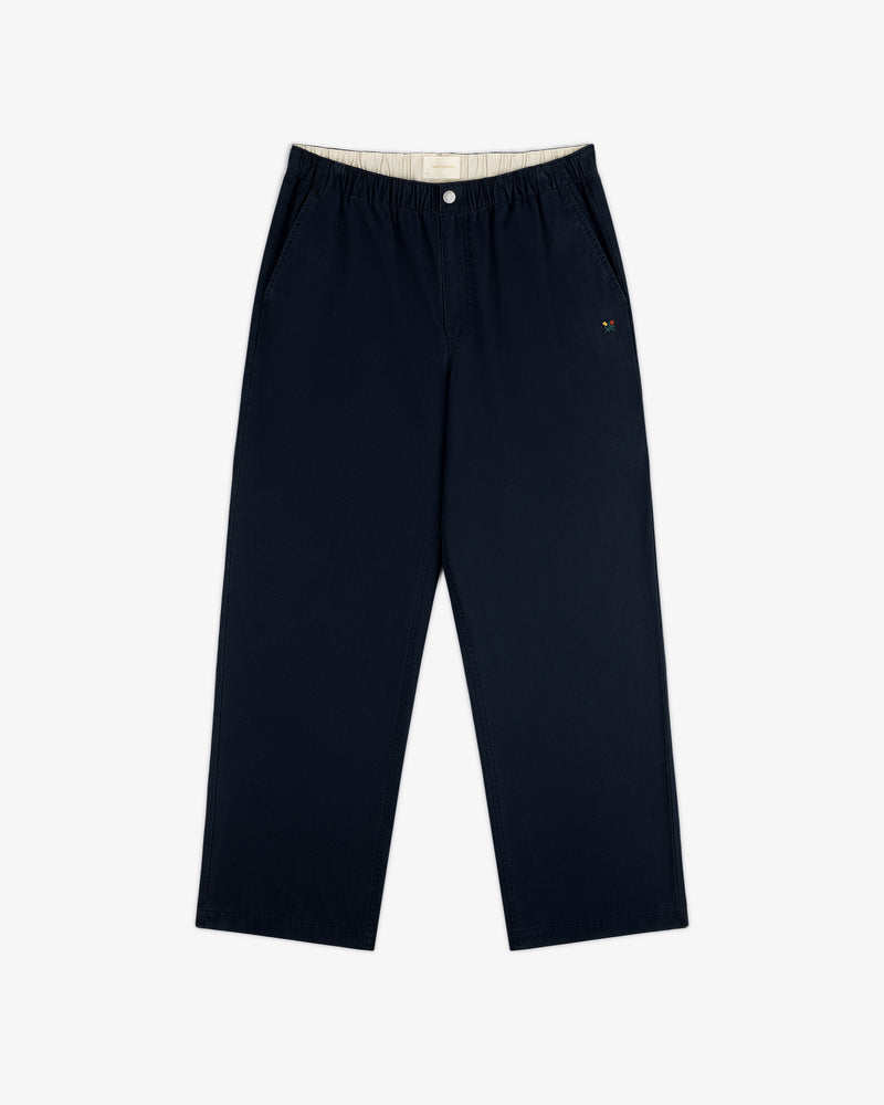 Washed Cotton Windbreaker Pant in navy blue features wide legs, elastic waistband, and small logo on left pocket.