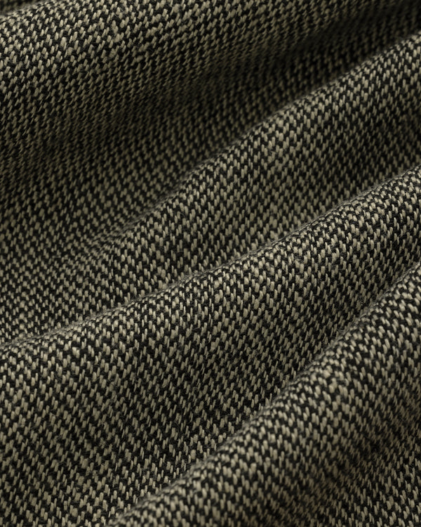 Close-up of Yarn Dyed Linen Suit Trouser fabric, featuring a textured black and white small check pattern with gentle folds.