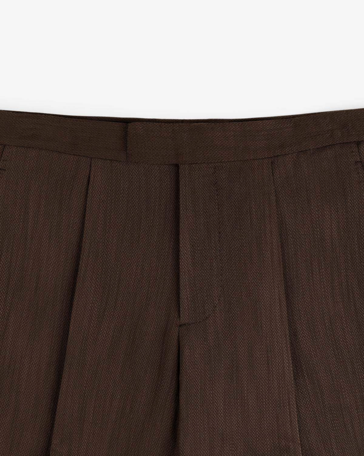 Close-up of the waistband and pleats of the Linen Blend Suit Trouser in brown against a white background.