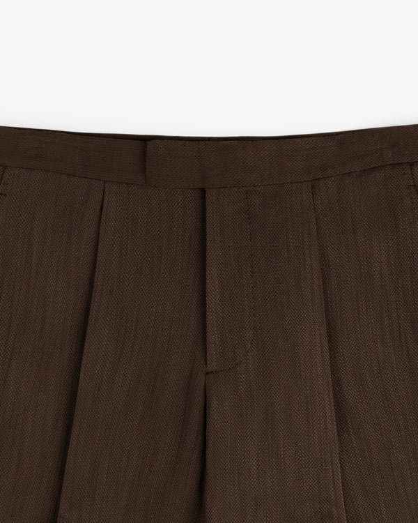 Close-up of the waistband and pleats of the Linen Blend Suit Trouser in brown against a white background.