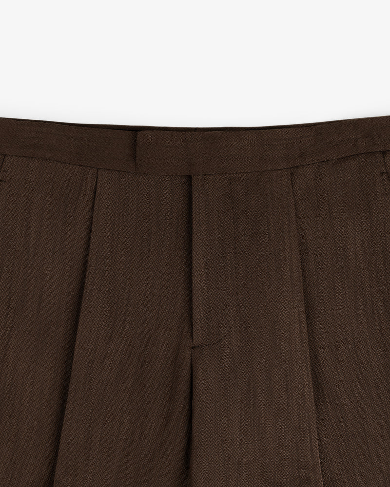 Close-up of the waistband and pleats of the Linen Blend Suit Trouser in brown against a white background.