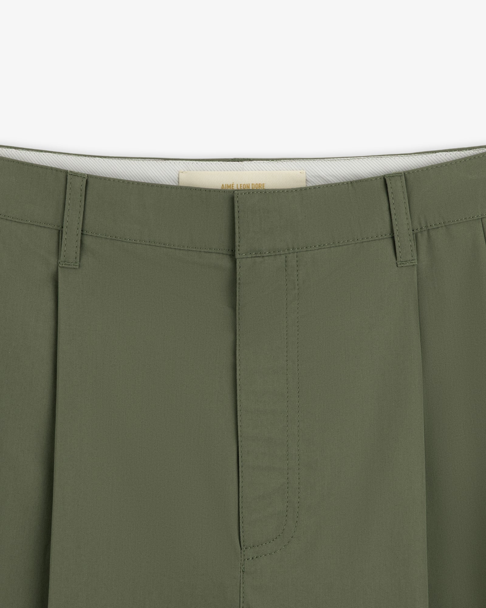 Close-up of the waistband and front of Lightweighted Pleated Cotton Trousers in olive with hidden hook-and-bar closure.