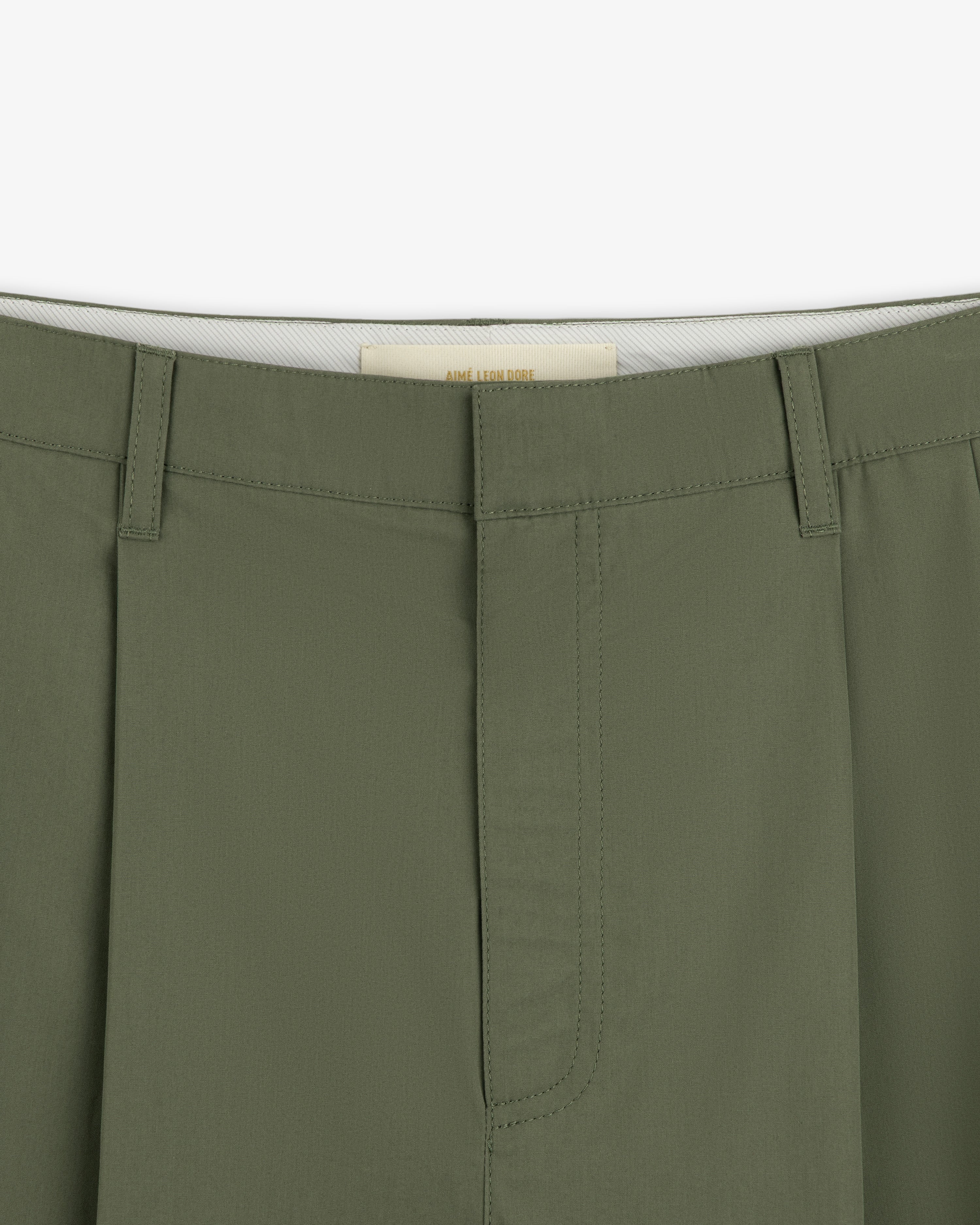 Close-up of the waistband and front of Lightweighted Pleated Cotton Trousers in olive with hidden hook-and-bar closure.