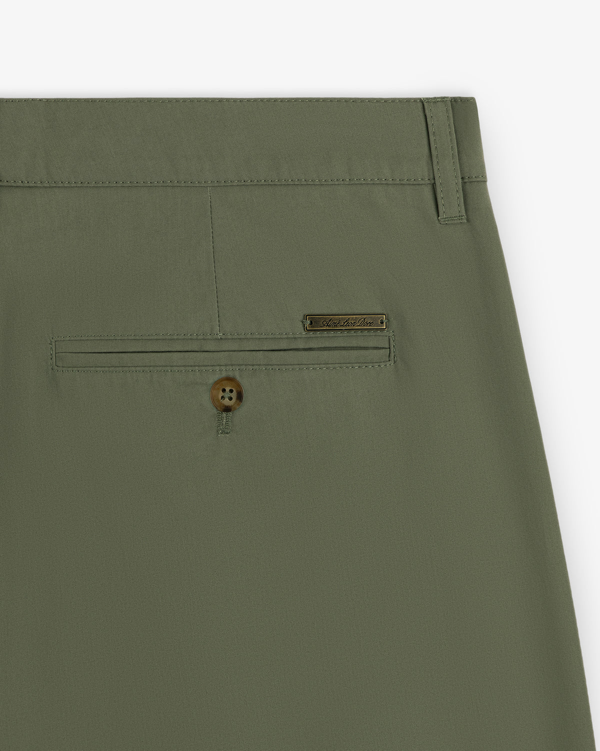 Close-up of Lightweighted Pleated Cotton Trouser in olive green with back pocket, button, and metal brand tag.