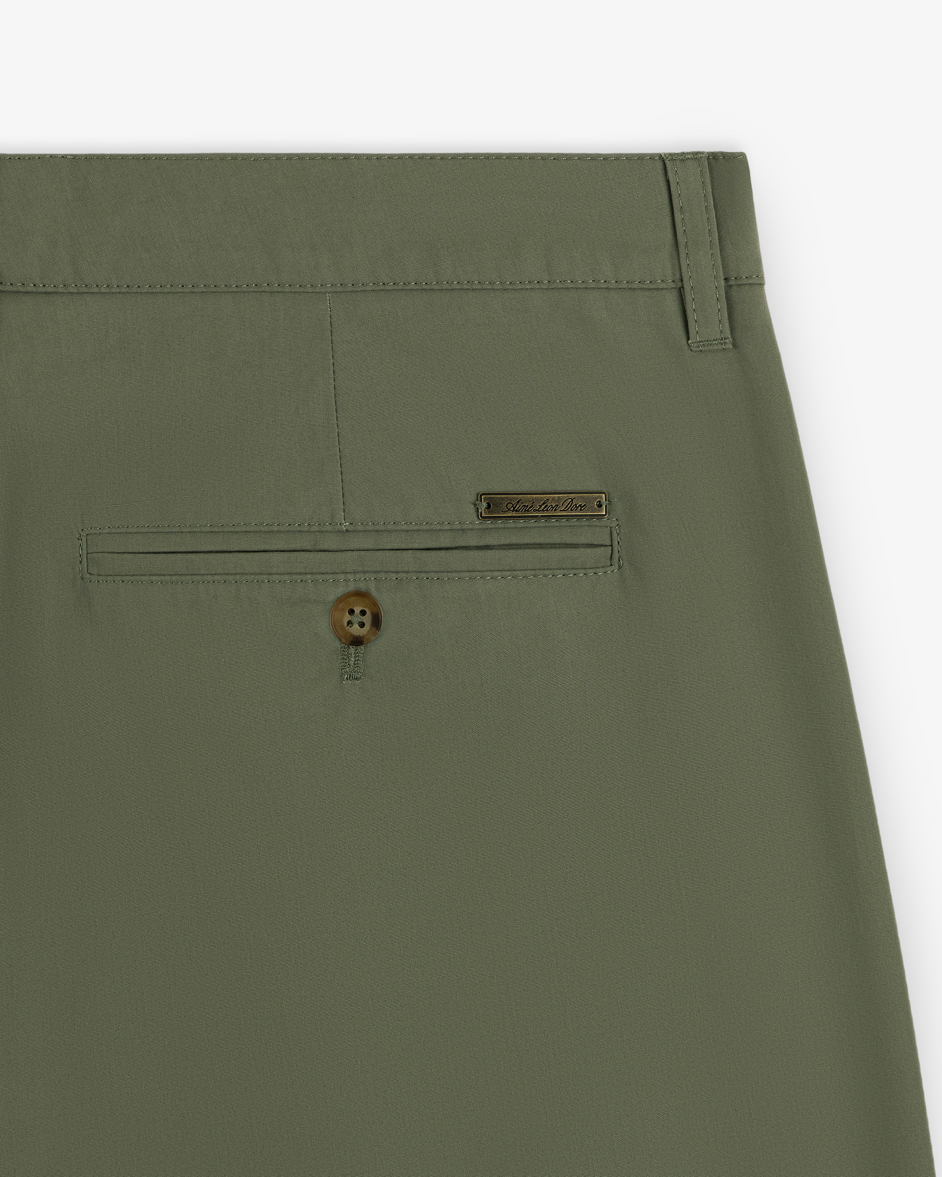Close-up of Lightweighted Pleated Cotton Trouser in olive green with back pocket, button, and metal brand tag.