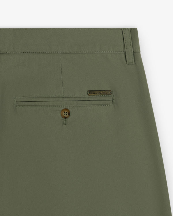 Close-up of Lightweighted Pleated Cotton Trouser in olive green with back pocket, button, and metal brand tag.
