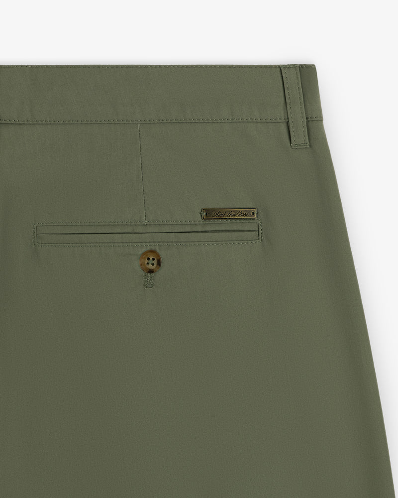 Close-up of Lightweighted Pleated Cotton Trouser in olive green with back pocket, button, and metal brand tag.