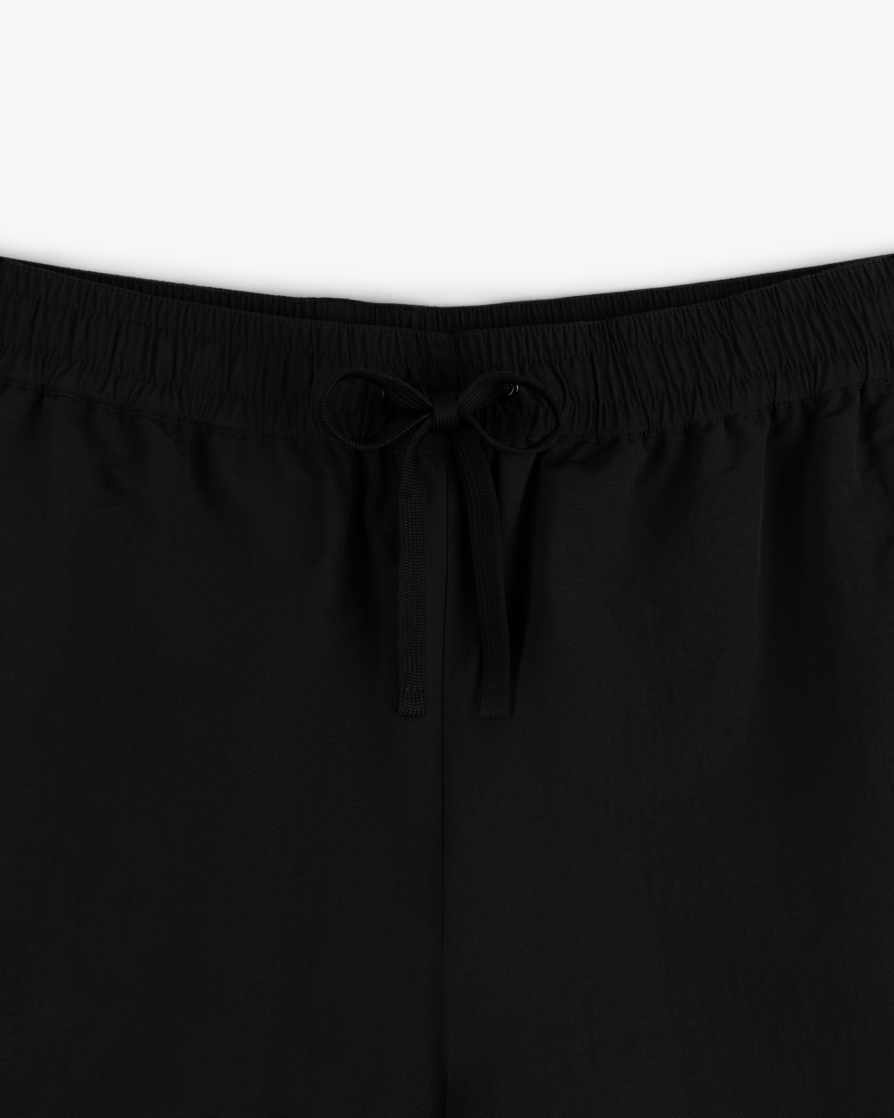 Close-up of Crest Nylon Track Pant in black featuring an elastic waistband and a center-tied drawstring bow.