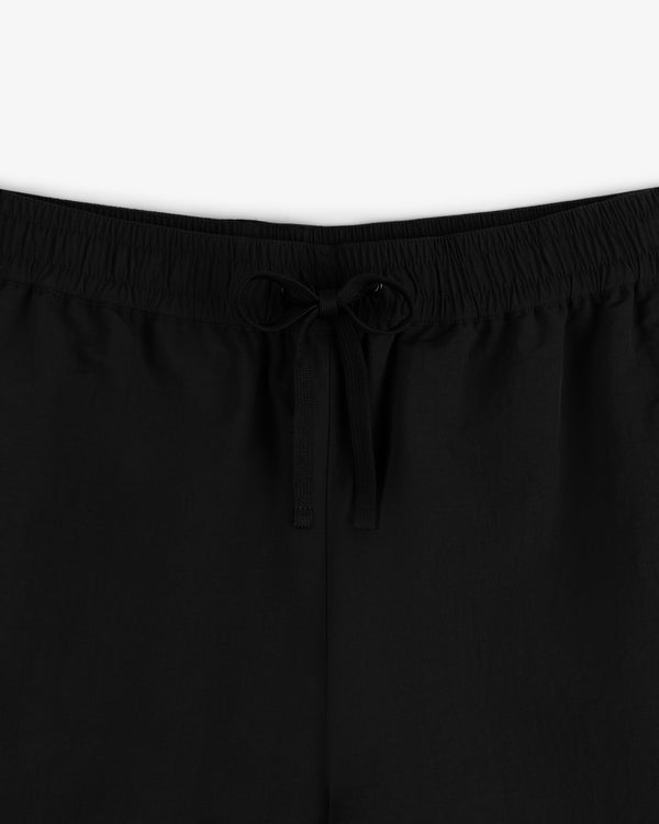 Close-up of Crest Nylon Track Pant in black featuring an elastic waistband and a center-tied drawstring bow.
