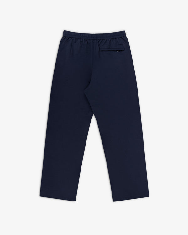 Crest Nylon Track Pant in navy blue with elastic waistband and zippered back pocket, shown flat on white.