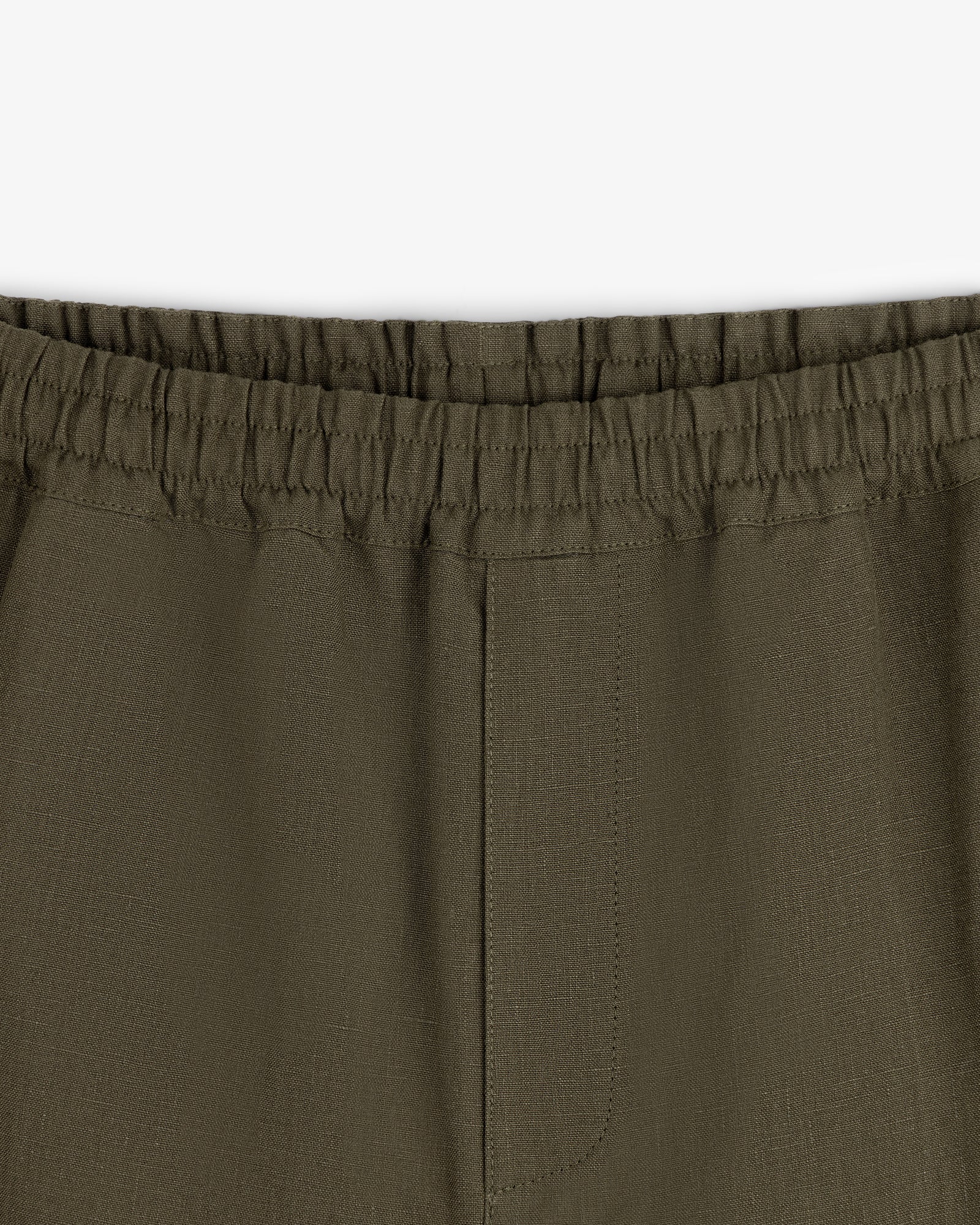 Close-up of Linen Leisure Pant in olive green with elastic waistband and center seam on white background.