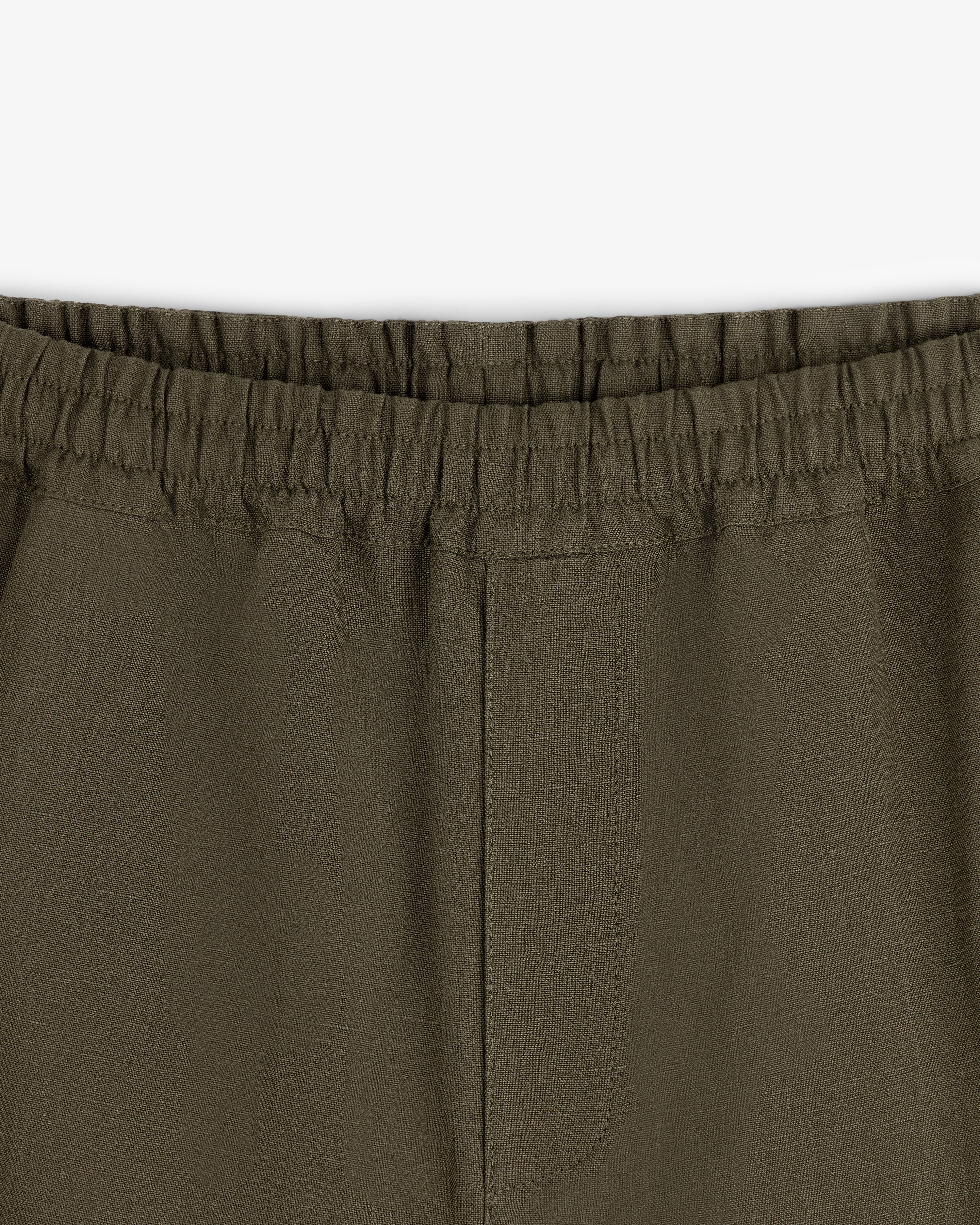 Close-up of Linen Leisure Pant in olive green with elastic waistband and center seam on white background.