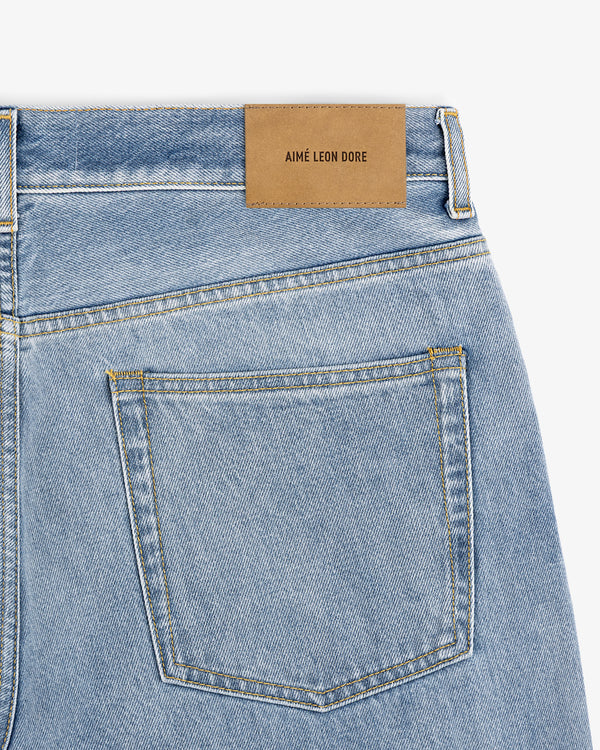 Close-up of Relaxed Fit 5-Pocket Denim Pant in light blue with a brown AIMÉ LEON DORE patch above the back pocket.