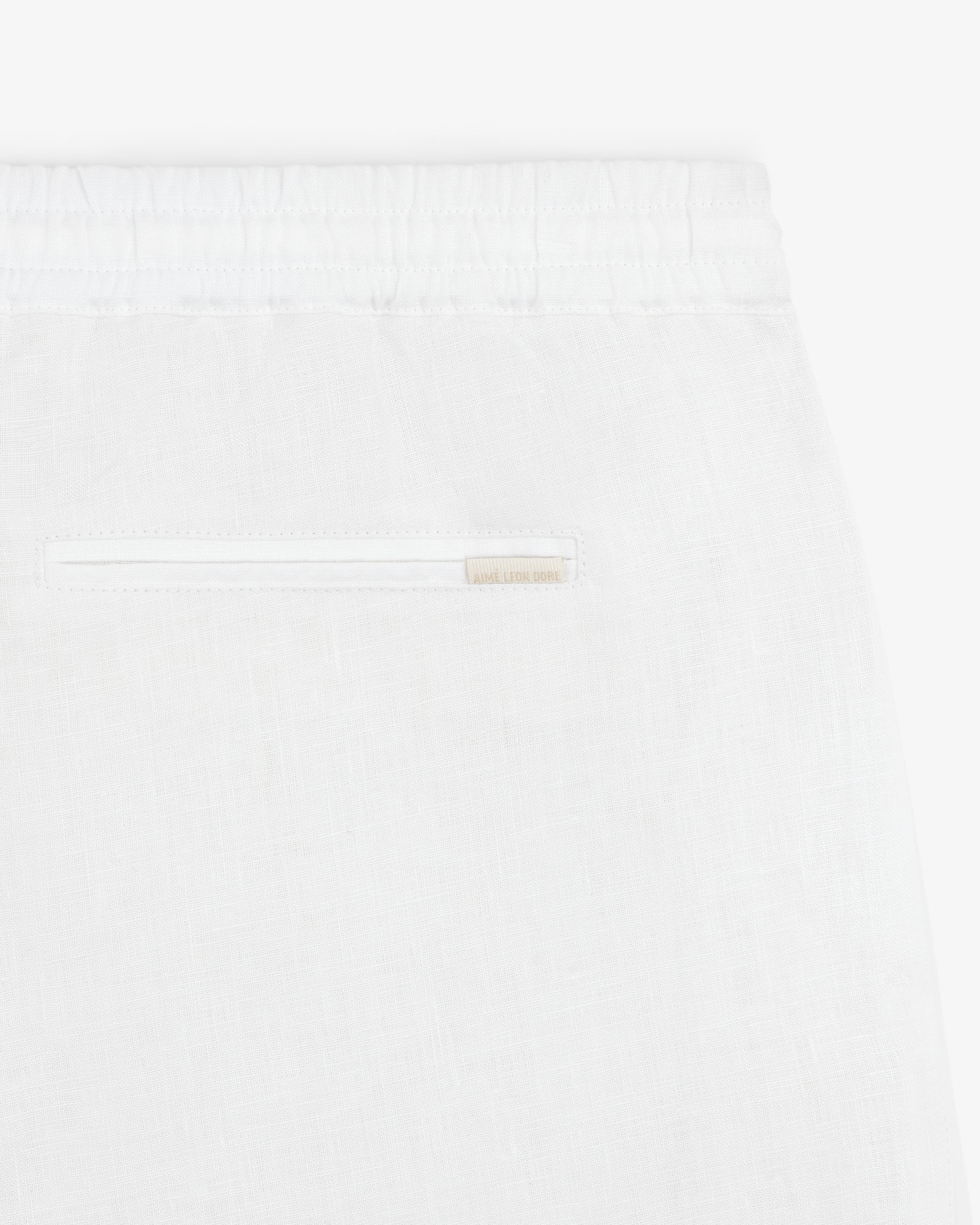 Close-up of Linen Leisure Pant in white, featuring an elastic waistband and a single back slit pocket.