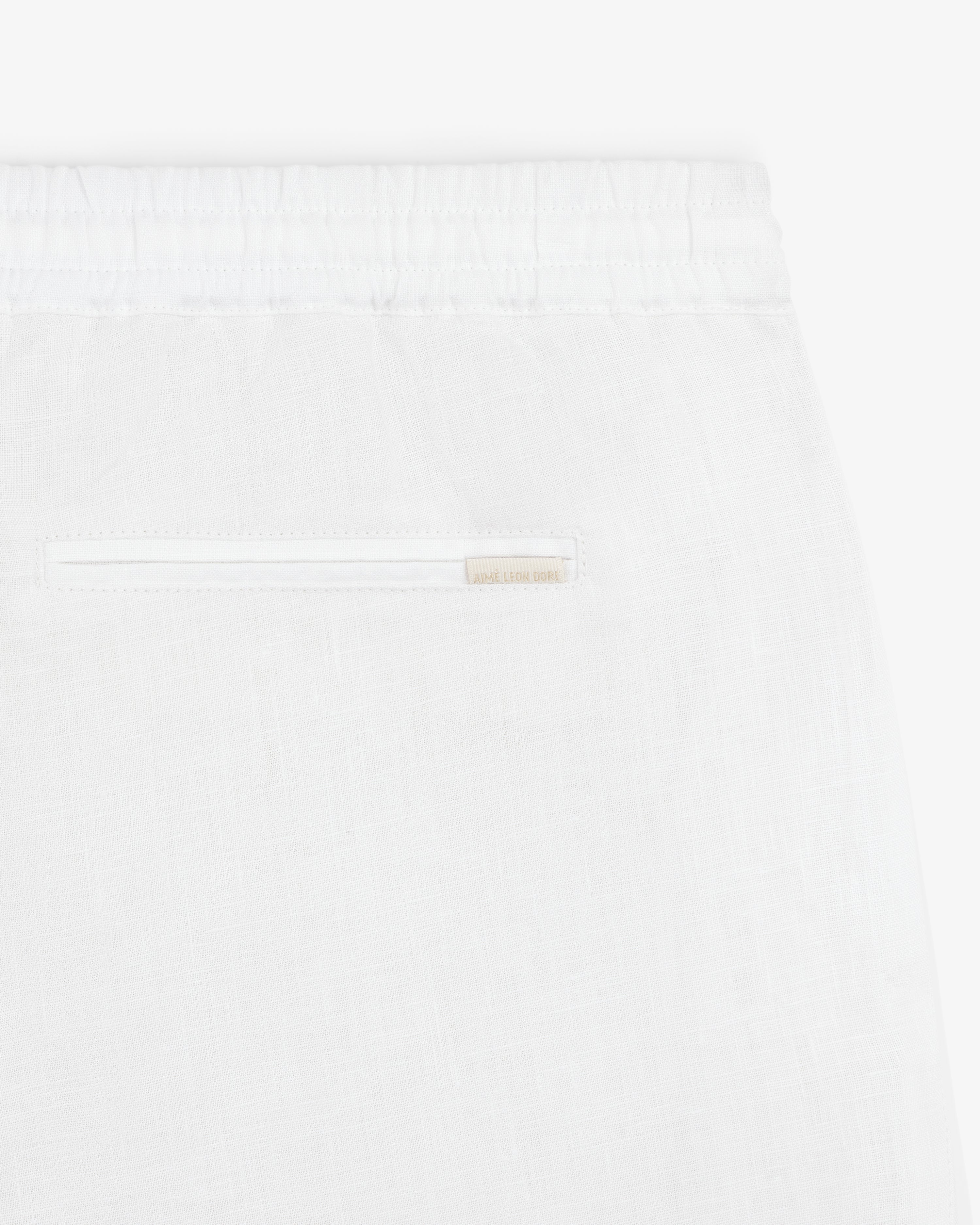Close-up of Linen Leisure Pant in white, featuring an elastic waistband and a single back slit pocket.