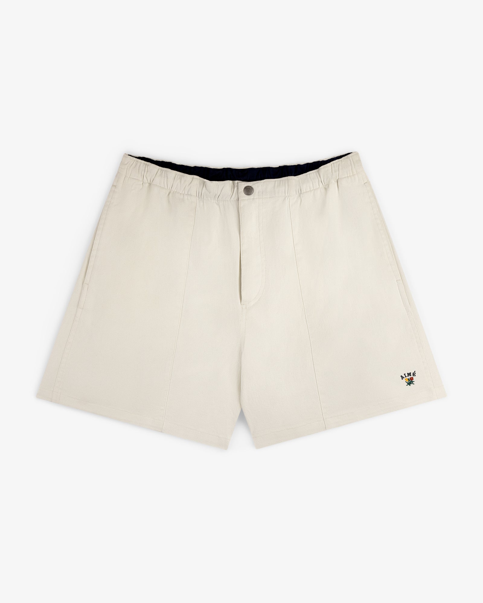 Crest Casual Short in beige with side pockets and a small floral embroidery near the hem, shown on white background.