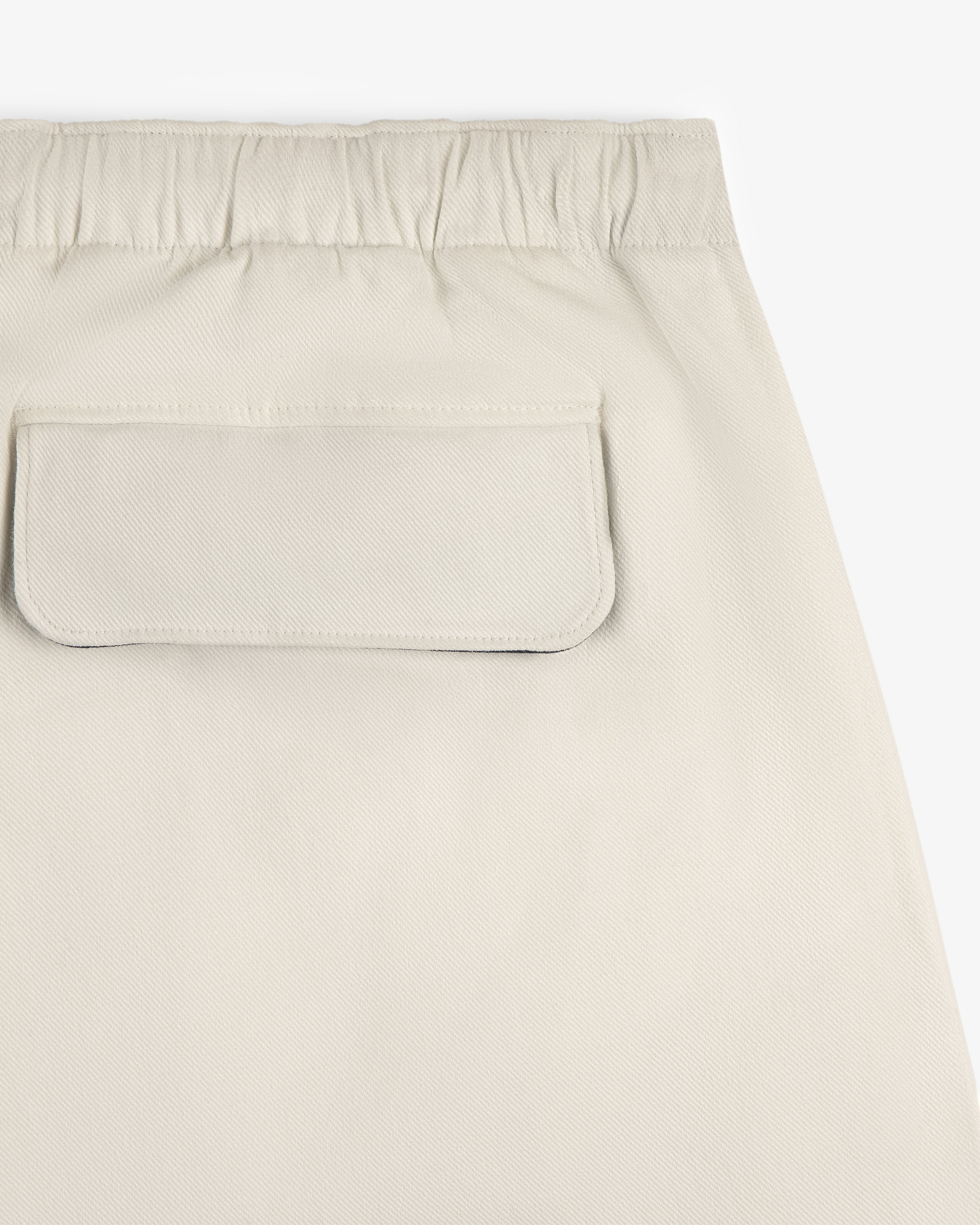 Close-up of Crest Casual Short in beige, featuring an elastic waistband and a back flap pocket.