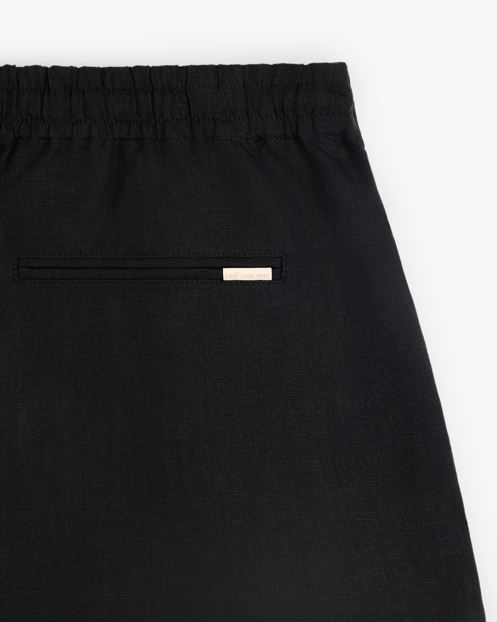 Close-up of the Linen Leisure Short in black, featuring an elastic waistband and a small back pocket with a label above.