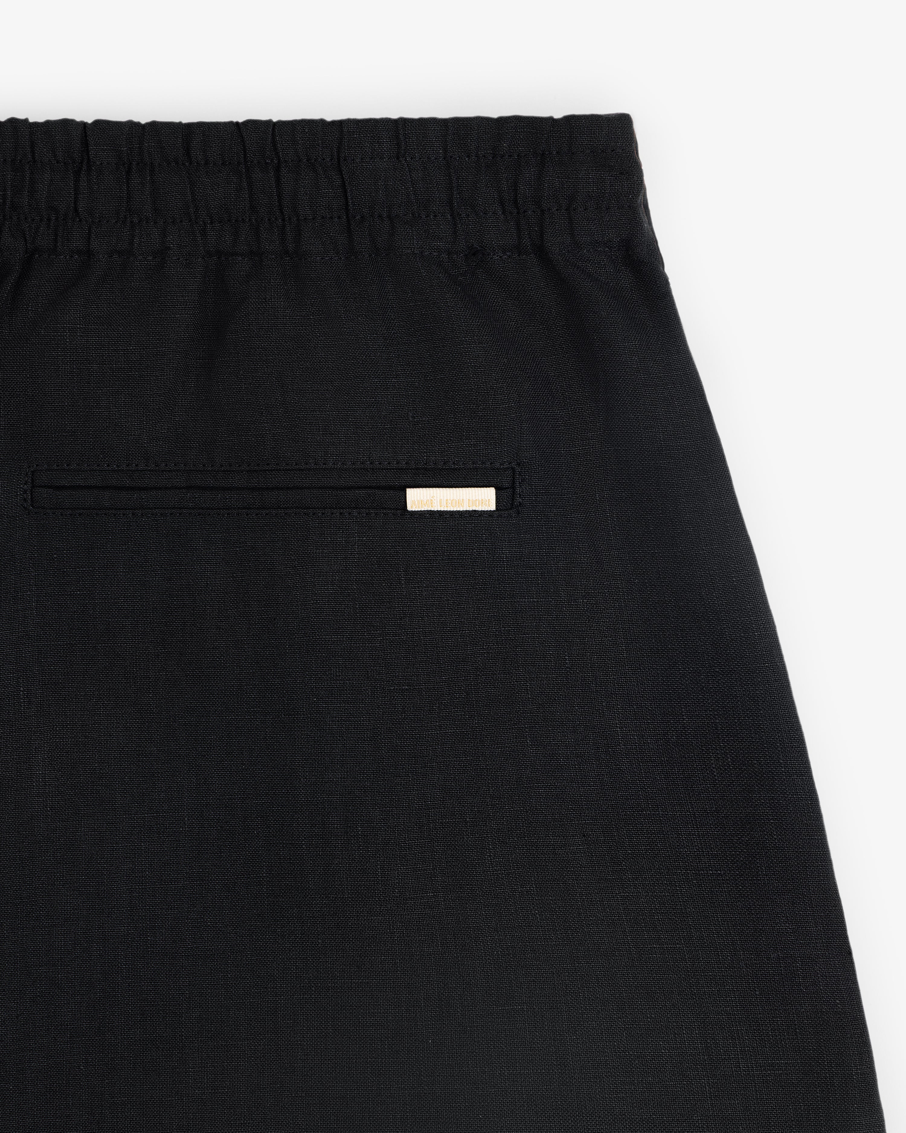Close-up of the Linen Leisure Short in black, featuring an elastic waistband and a small back pocket with a label above.