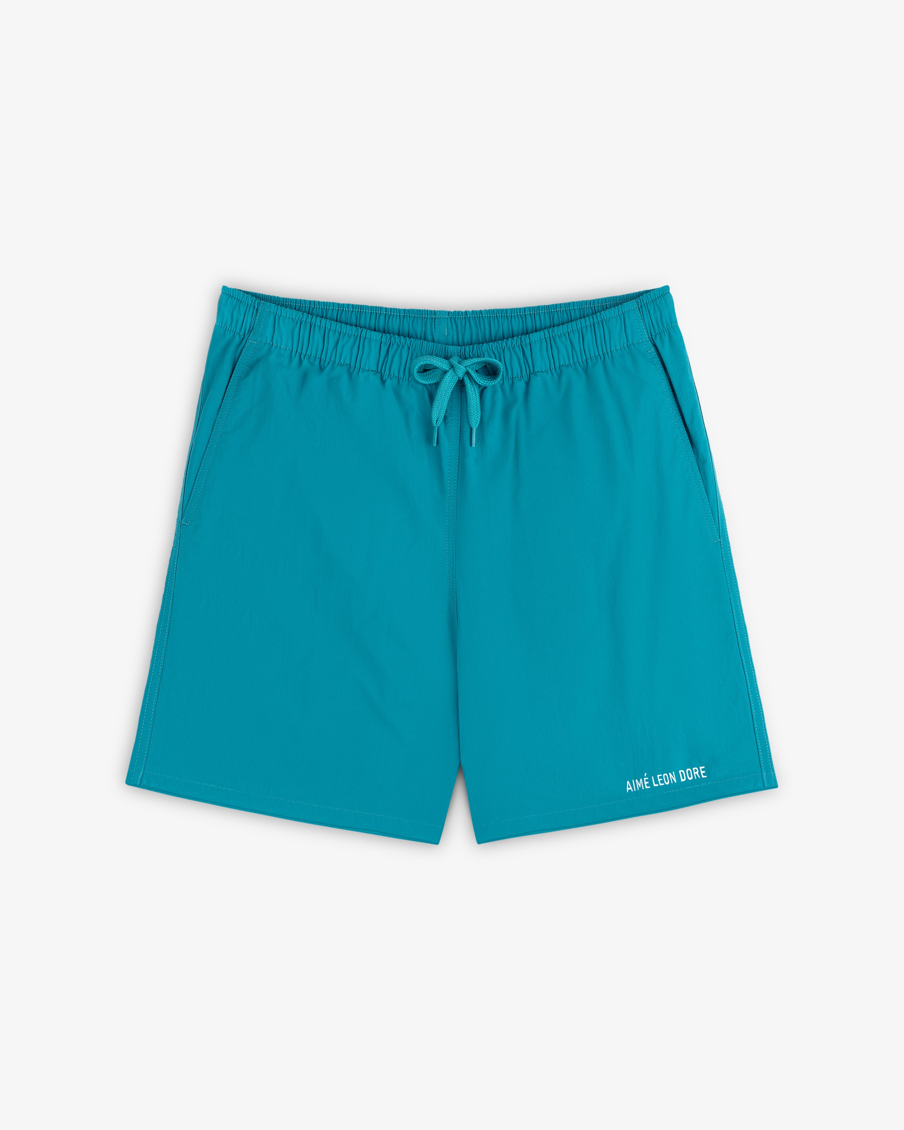 Logo Swim Short in bright turquoise with elastic waistband, drawstring, side pockets, and logo text on the hem.