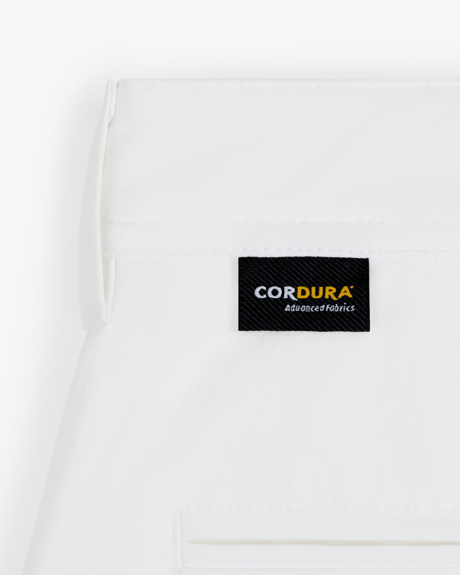 A white ALD Golf Cordura Double Pleated Short with a black CORDURA Advanced Fabrics label sewn near the seam.