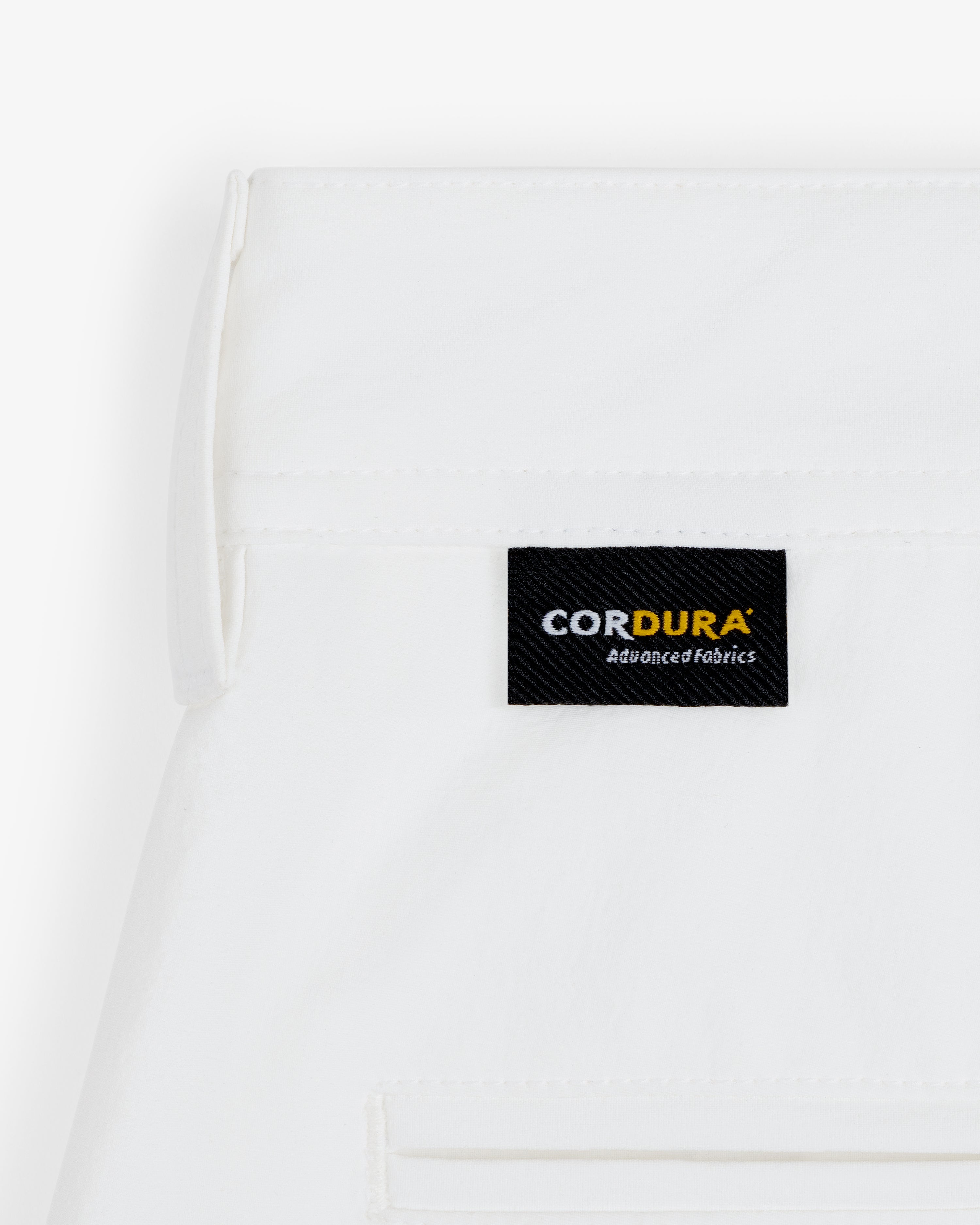 A white ALD Golf Cordura Double Pleated Short with a black CORDURA Advanced Fabrics label sewn near the seam.