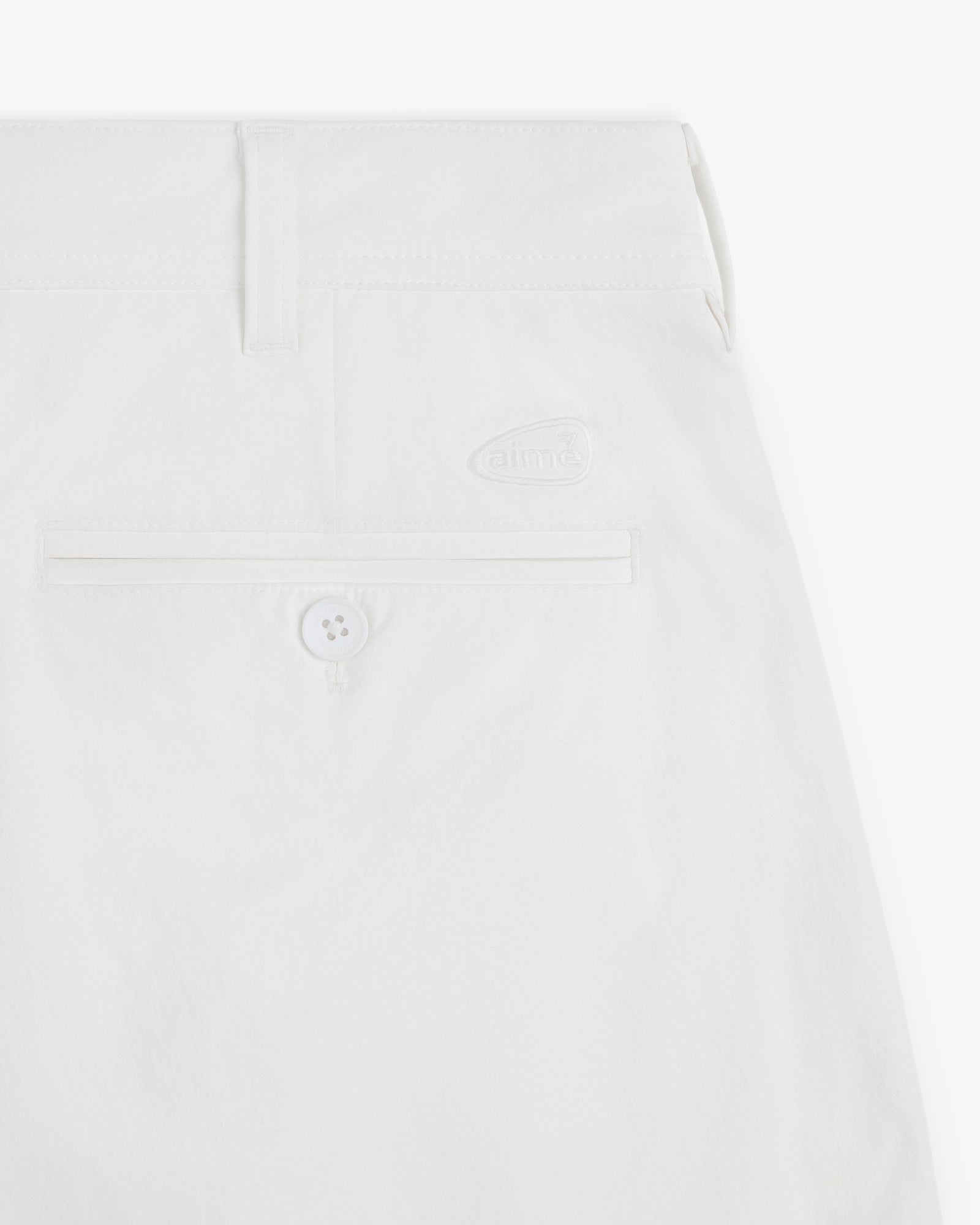 Close-up of ALD Golf Cordura Double Pleated Short in white, with a back pocket, button, belt loop, and logo detail.