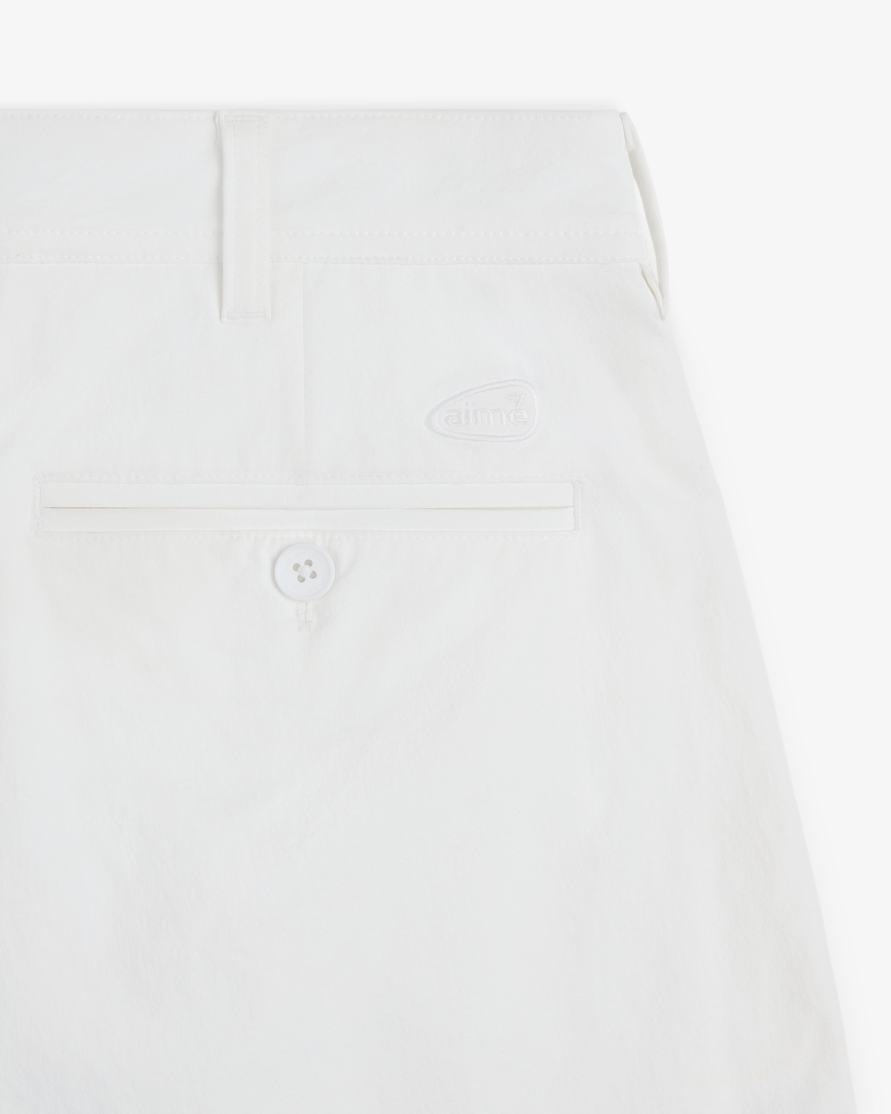 Close-up of ALD Golf Cordura Double Pleated Short in white, with a back pocket, button, belt loop, and logo detail.