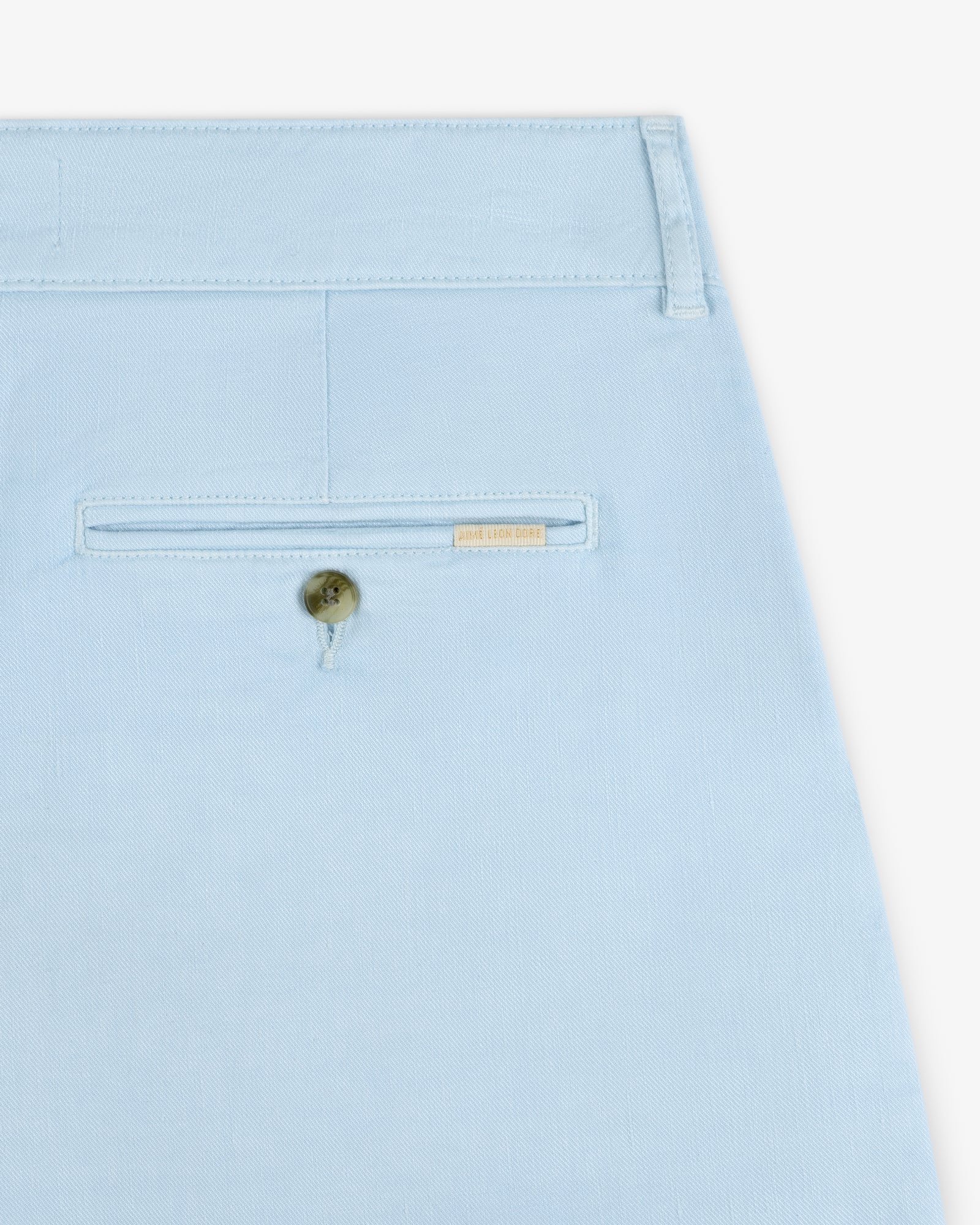 Close-up of a light blue Pleated Linen Blend Bermuda Short pocket with a button and a small gold label above it.