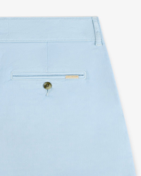 Close-up of a light blue Pleated Linen Blend Bermuda Short pocket with a button and a small gold label above it.