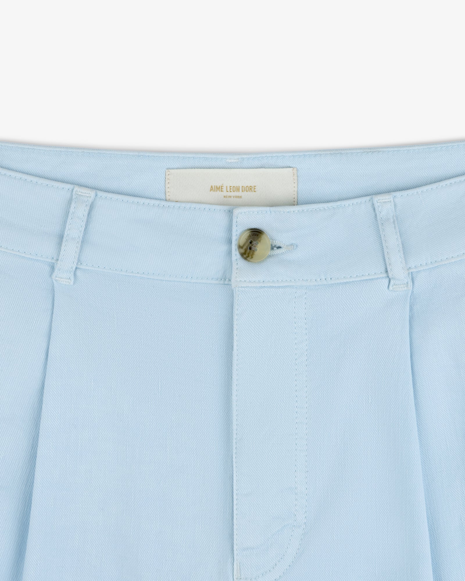 Close-up of Pleated Linen Blend Bermuda Short in light blue with belt loops, button closure, and AIME LEON DORE label.
