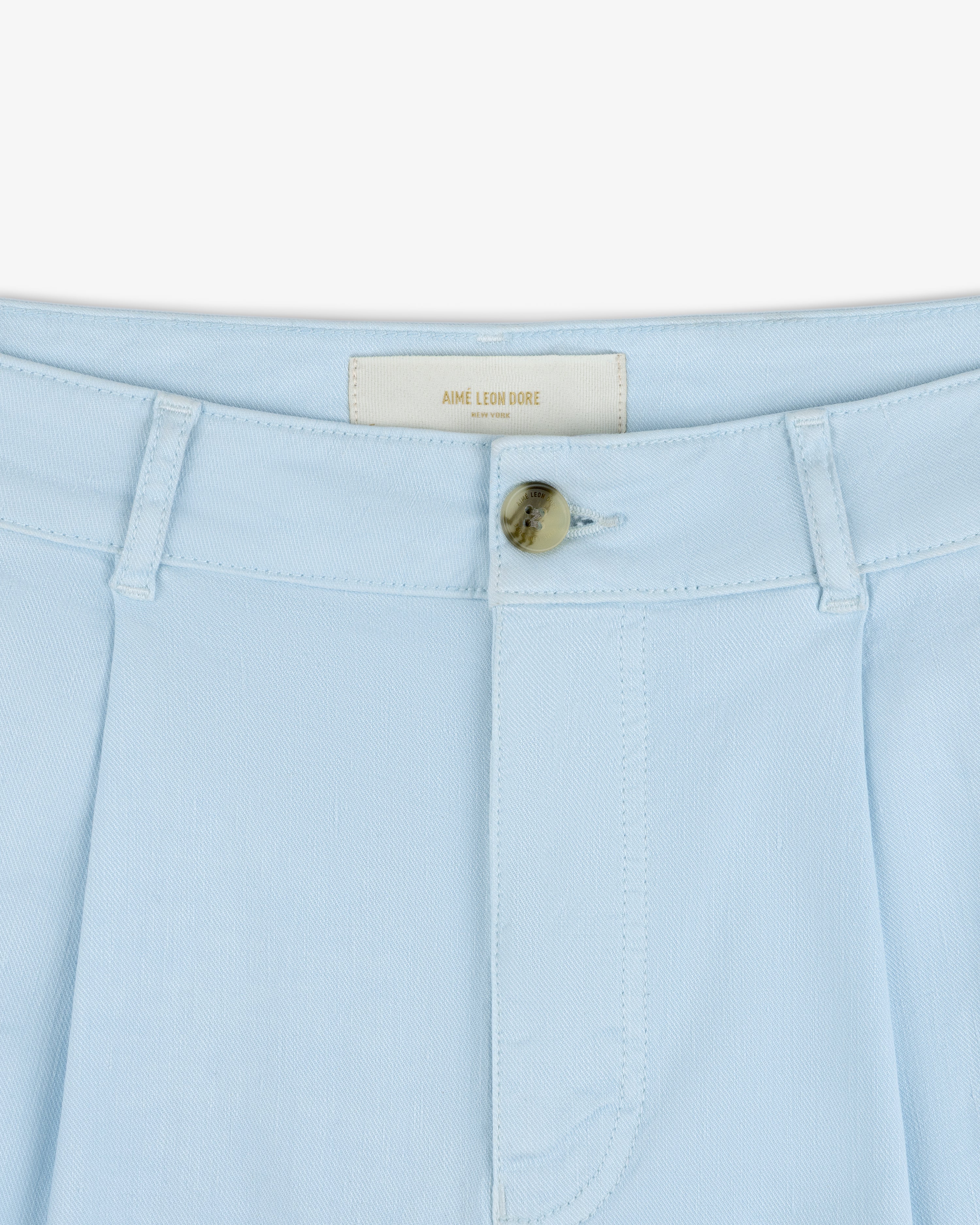 Close-up of Pleated Linen Blend Bermuda Short in light blue with belt loops, button closure, and AIME LEON DORE label.