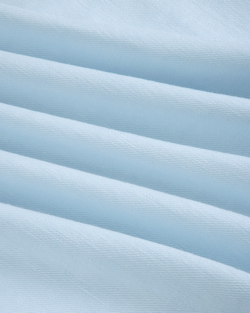 Close-up of Pleated Linen Blend Bermuda Short in light blue, showing soft folds and a textured surface.