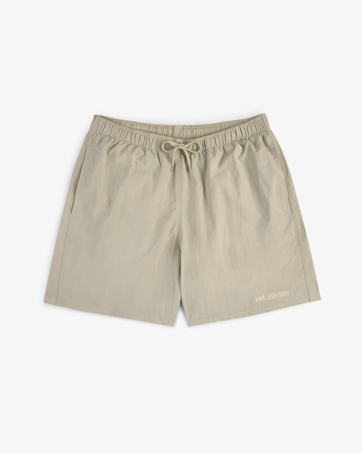 Core Nylon Short in beige with drawstring waist, side pockets, and AIMÉ LEON DORE logo on the bottom left leg.