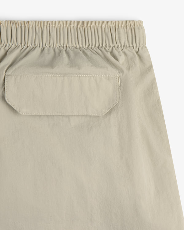 Close-up of the back of Core Nylon Short in beige, featuring an elastic waistband and a flap pocket.