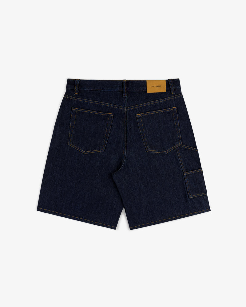 Back view of Rinse Wash Denim Short with contrast stitching, patch pockets, side utility pocket, and tan waist label.