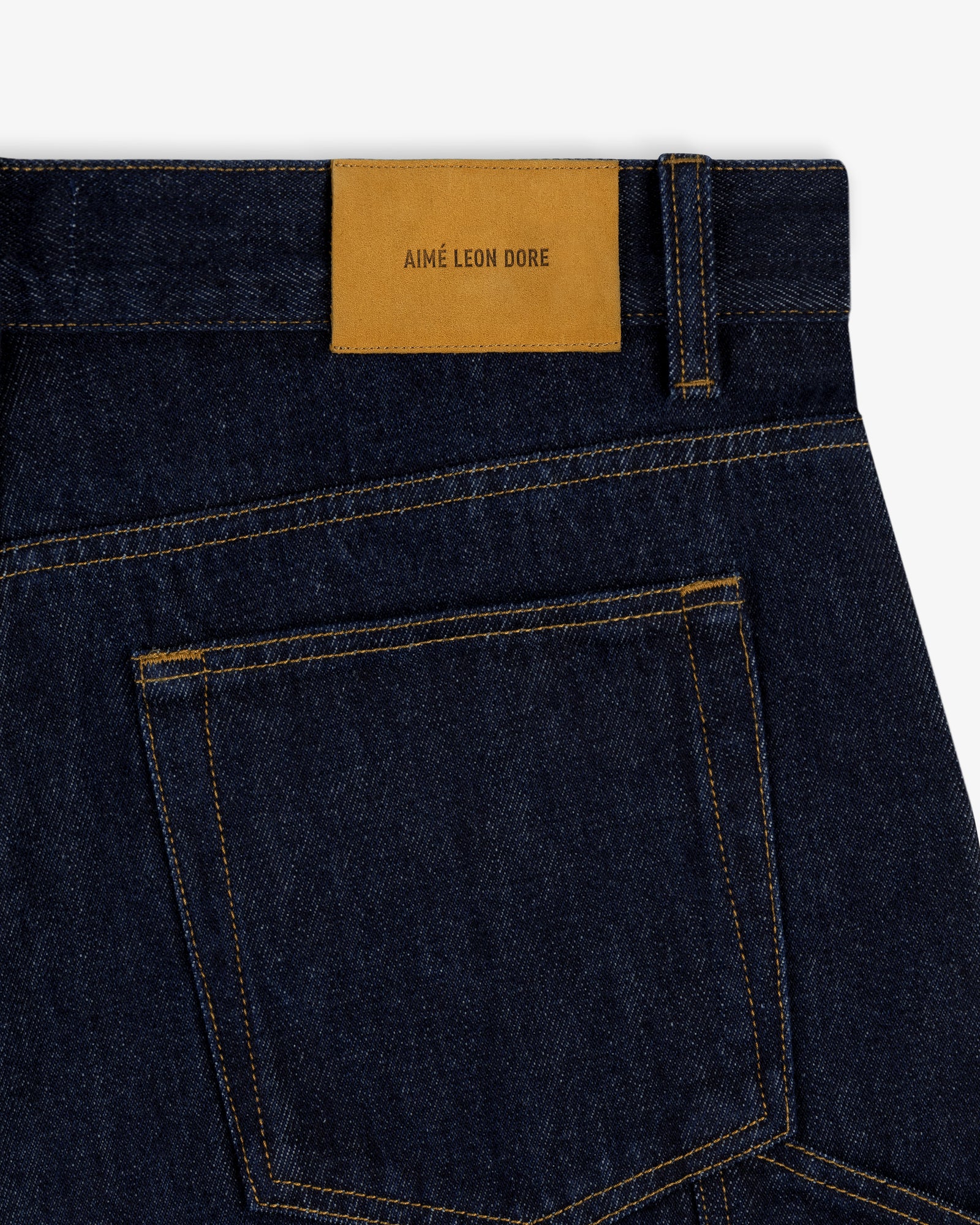 Rinse Wash Denim Short in dark blue with yellow stitching and a tan AIMÉ LEON DORE leather patch above the back pocket.
