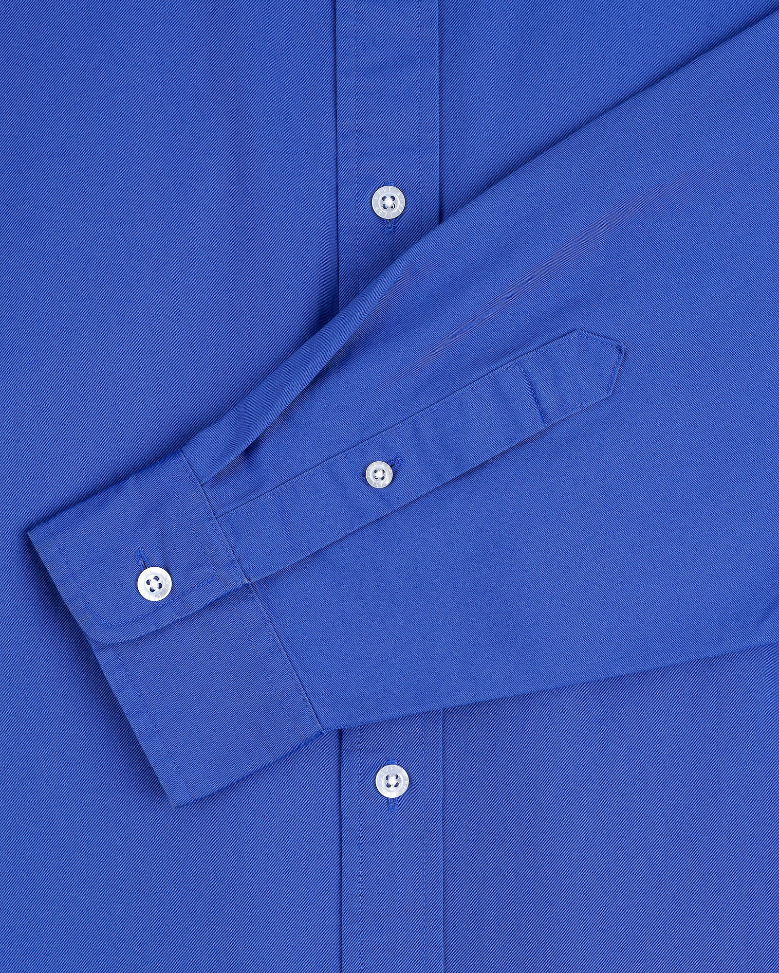 Close-up of the Leon Overshirt in blue, highlighting the sleeve and white buttons.