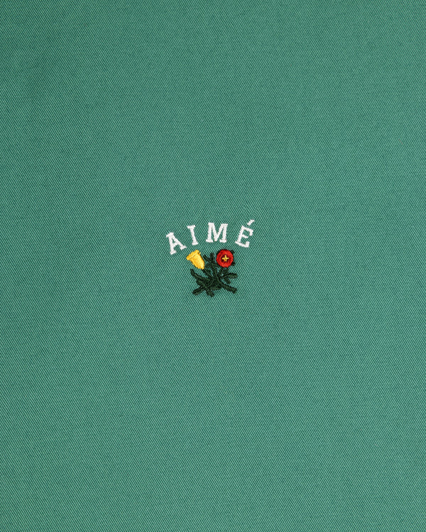 The Leon Overshirt features green fabric with AIMÉ embroidered above yellow and red flowers with green leaves.