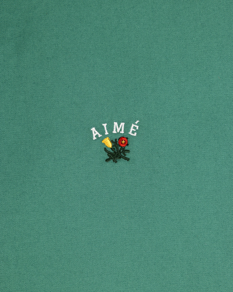 The Leon Overshirt features green fabric with AIMÉ embroidered above yellow and red flowers with green leaves.