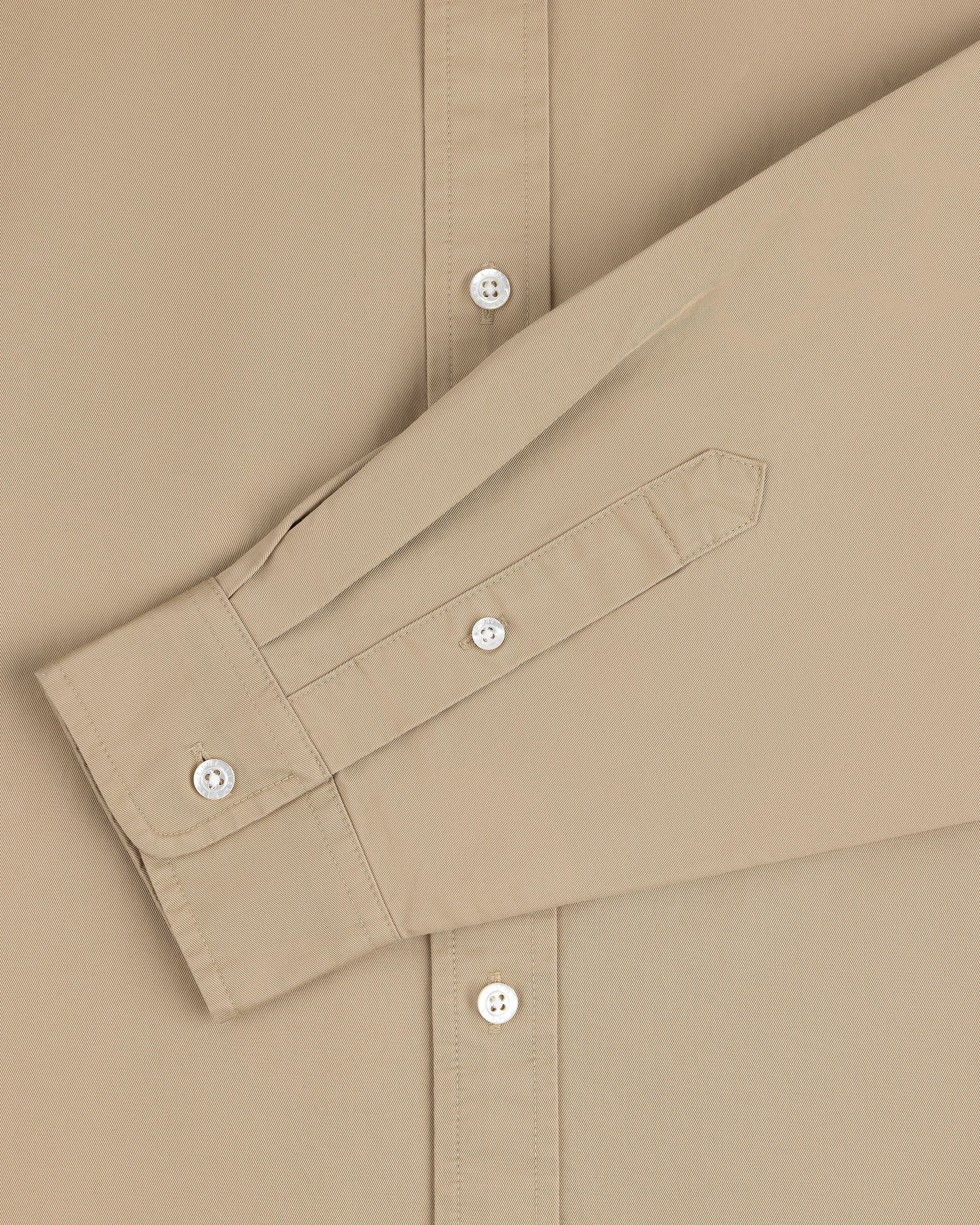 The Leon Overshirt in beige features white buttons and a long sleeve folded neatly across the front.