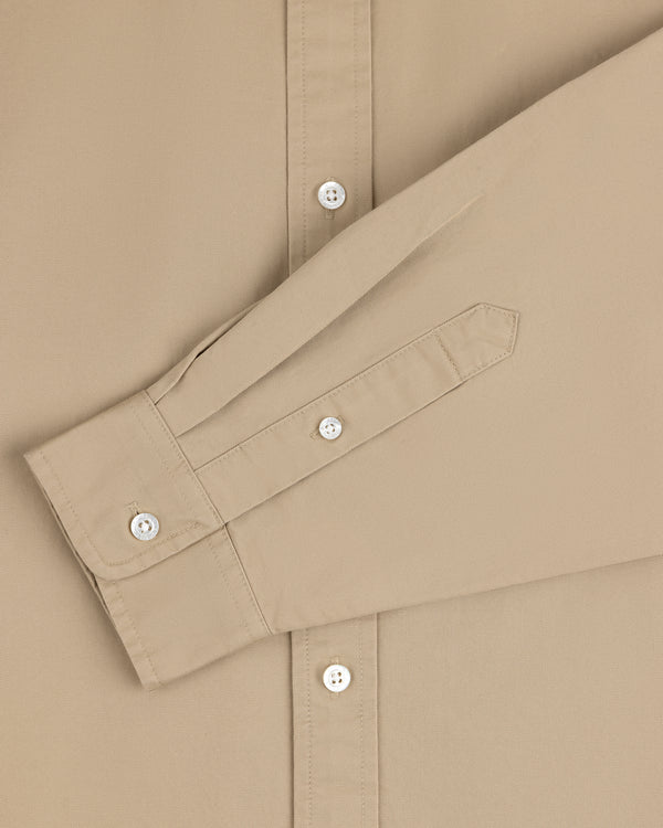 The Leon Overshirt in beige features white buttons and a long sleeve folded neatly across the front.