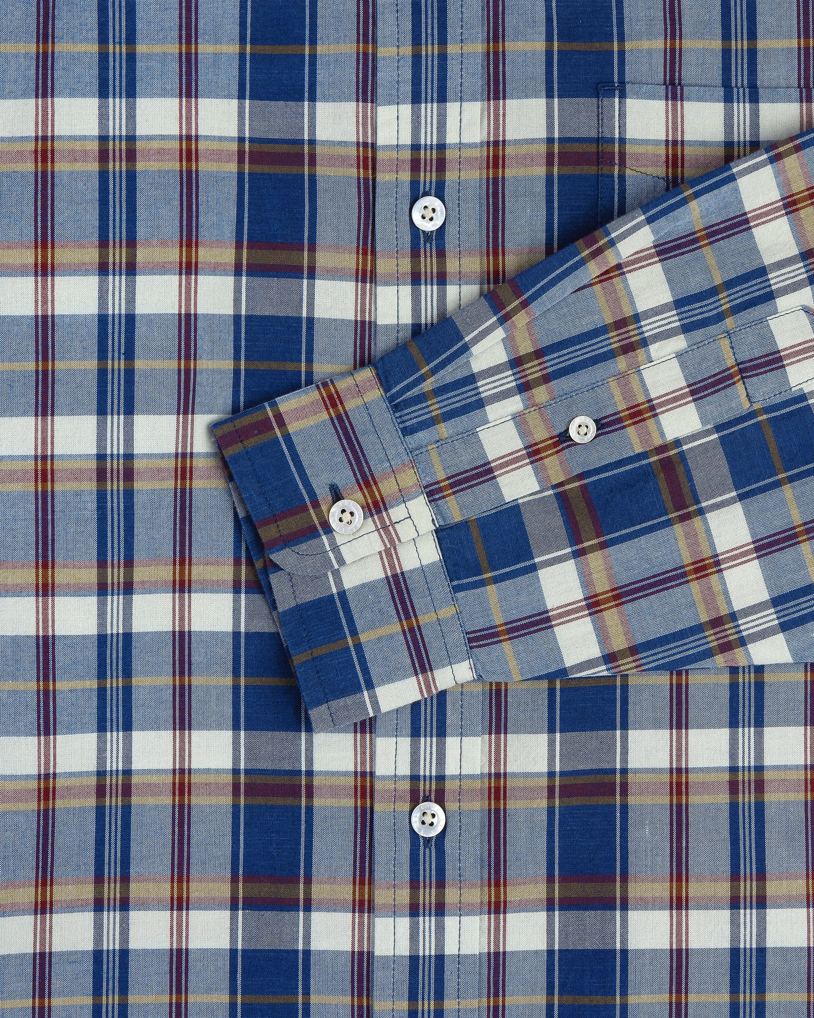 Washed Madras Shirt in blue, yellow, and white plaid with one sleeve folded diagonally across the chest.