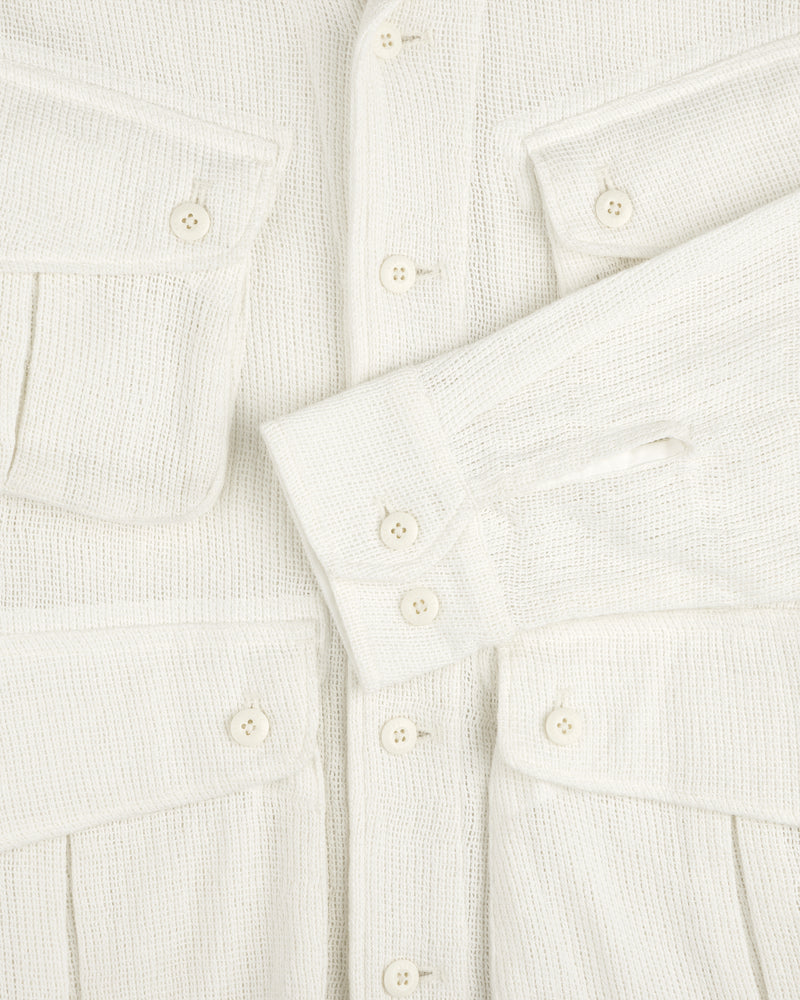 Close-up of the Mesh Jungle Shirt, cream-colored with textured fabric, buttons, flap pockets, and one sleeve across the front.